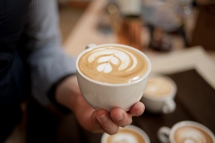 カフェラテのカップを持つ人