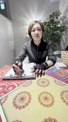 雨照 占い館アメテラス 渋谷店の鑑定ブースで、相談を聞きながらメモをとる夢宵 もよ先生